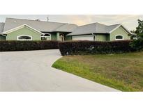 Charming single-story home with a well-manicured lawn, concrete driveway, and lush green landscaping at 2910 Ne 24Th Pl, Ocala, FL 34470