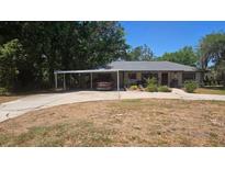Charming single-story home featuring a covered carport and a well-maintained front yard at 408 Etheredge St, Bushnell, FL 33513