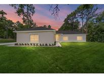 Charming single-story home with lush green lawn, landscaping, and a colorful sunset at 8498 Sw 129Th Terrace Rd, Dunnellon, FL 34432