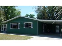 Charming single-story green home with a covered carport and well-maintained front lawn at 9880 Sw 101St Pl, Ocala, FL 34481