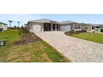 Beautiful single-Gathering home featuring a three car garage and a brick-paved driveway and walkway at 10082 Sw 82Nd Place Rd, Ocala, FL 34481