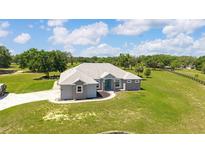 Beautiful single-story home featuring a well-manicured lawn, stylish stone accents and a welcoming, turquoise front door at 5489 Nantahala Ln, Lady Lake, FL 32159