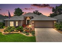 Charming single-story home with manicured lawn, landscaped flower beds, and inviting front porch, illuminated by beautiful twilight at 8545 Se 168Th Kittredge Loop, The Villages, FL 32162