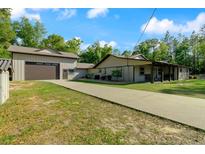 Charming home featuring a long driveway, two-car garage and carport on a beautifully wooded lot at 11806 Sw 61St Place Rd, Ocala, FL 34481