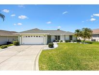 Charming single-story home with a well-manicured lawn and clean, white driveway at 12147 Se 173Rd Pl, Summerfield, FL 34491