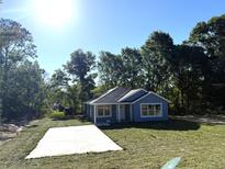 Charming single-story home with a light blue exterior, white trim, and a well-manicured front lawn at 14173 Se 41St Ter, Summerfield, FL 34491