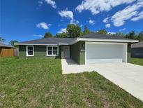 Charming single-story home features an attached two-car garage and a well-manicured lawn at 235 Locust Pass Ln, Ocala, FL 34472