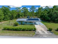 Charming single-story home featuring solar panels, a covered carport, and a well-manicured front yard at 23737 Nw Mallard Ave, Dunnellon, FL 34431