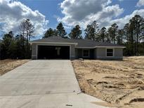 New construction featuring a concrete driveway, gray exterior paint, and dark gray roof at 4374 Sw Viola Ct, Dunnellon, FL 34431
