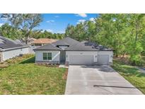 Charming single-story home with a two-car garage, landscaped front yard, and modern architectural details at 9405 Se 159Th Ln, Summerfield, FL 34491
