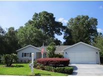 Charming single-story home with well-manicured lawn and mature trees under a clear blue sky at 14272 Sw 112Th Cir, Dunnellon, FL 34432