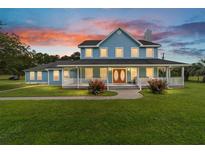 Charming two-story home featuring a welcoming front porch and a beautifully landscaped lawn with a vibrant sunset backdrop at 20921 Sw 36Th St, Dunnellon, FL 34431