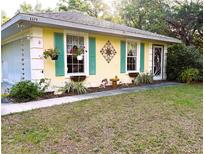 Charming exterior featuring a cheerful yellow facade, complemented by vibrant turquoise shutters and blossoming flower boxes at 3579 Sw Shorewood Dr, Dunnellon, FL 34431