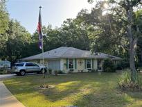 Charming one-story home featuring a lush front lawn, mature trees, and a welcoming facade at 3579 Sw Shorewood Dr, Dunnellon, FL 34431