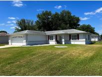 Charming single-story home with a well-maintained lawn and a two-car garage, under a blue sky at 6070 Sw 98Th Loop, Ocala, FL 34476