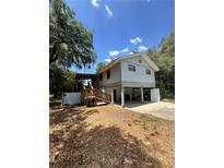 Unique home featuring a covered porch entry with wooden stairs and a stilt foundation at 6498 Se 167Th Ct, Ocklawaha, FL 32179