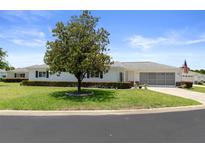 Charming single-story home featuring a well-manicured lawn, mature tree, and attached two-car garage at 13618 Sw 111Th Cir, Dunnellon, FL 34432