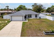 Charming single-story home with a well-manicured lawn, attached garage, and a white picket fence at 14118 Sw 32Nd Terrace Rd, Ocala, FL 34473