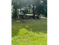 Quaint single-story home featuring a lush green lawn and charming wooden fence at 14121 Nw Highway 225, Reddick, FL 32686