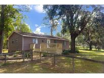 Charming single-story home featuring a covered porch, wood siding, and a well-maintained front yard with mature trees at 14121 Nw Highway 225, Reddick, FL 32686