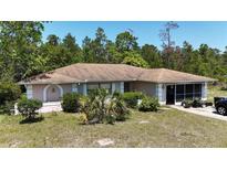 Single story home with neutral paint, brown roof, decorative shrubs, and a screened in lanai at 15920 Sw 49Th Court Rd, Ocala, FL 34473