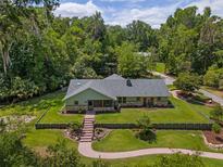 Charming single-story home with stone accents, gray roof, walkway and beautifully manicured lawn, surrounded by mature trees at 400 Se 90Th St, Ocala, FL 34480