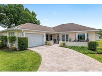 Well-maintained single-story home featuring an attached garage, landscaped front yard, and curved brick driveway at 6858 Sw 111Th Loop, Ocala, FL 34476