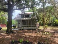 Quaint home nestled among mature trees and shrubbery with a screened front porch and metal roof at 10805 Se 102Nd Pl, Ocala, FL 34472