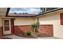 Inviting front entrance with red brick planter and matching door, offering a warm welcome at 12 Brook Pl, Ocala, FL 34472
