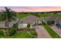 Charming single-story home with manicured landscaping and a view of the golf course at sunset at 12255 Se 177Th Loop, Summerfield, FL 34491