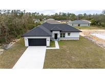 Beautiful single-story home boasts a dark garage, complementary black roof, and a well-manicured lawn at 16890 Sw 39Th Cir, Ocala, FL 34473