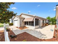 Charming home featuring a paved patio, screened-in porch, manicured landscaping, and a white picket fence at 1736 Watts Mill Way, The Villages, FL 32162