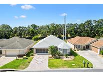 Aerial view of a well-maintained home with lush landscaping, screened in porch, and brick driveway at 17902 Se 115Th Cir, Summerfield, FL 34491