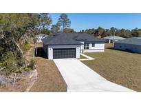 Charming one-story home featuring a two-car garage and a modern design with gray paint and a concrete driveway at 2627 Sw 154Th Place Rd, Ocala, FL 34473