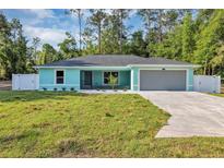 Charming single-story home boasts a manicured lawn, gray roof, an attached two car garage, and a light blue exterior at 4314 Se 131St Ln, Belleview, FL 34420