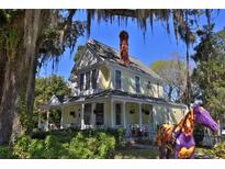 Charming yellow two-story home with a welcoming front porch and colorful horse statue at 743 E Fort King St, Ocala, FL 34471
