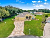 Beautiful home featuring a 3-car garage, meticulously landscaped yard, and a patterned concrete driveway under a sunny sky at 13885 Del Webb Blvd, Summerfield, FL 34491