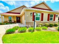 Charming single-story home featuring a well-manicured lawn and colorful landscaping with red shutters, and a red roof at 3023 Charlevoix St, The Villages, FL 32163
