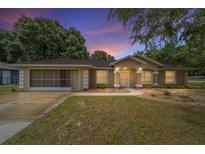 Charming single-story home featuring a well-maintained lawn, screened garage and an inviting entrance at twilight at 4886 Nw 30Th Pl, Ocala, FL 34482