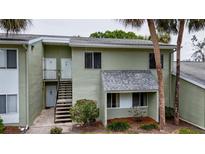Two-story condo with light-green exterior, stairs to the second floor, and mature trees surrounding the property at 559 Fairway Circle # A, Ocala, FL 34472