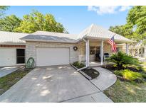 Charming single-story home with a brick facade, attached garage, and a cozy front porch adorned with an American flag at 8712 Sw 92Nd St # C, Ocala, FL 34481