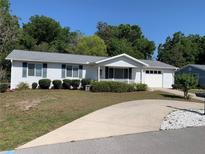 Well-kept home featuring a manicured lawn, a paved driveway, and an attached garage at 11445 Sw 84Th Avenue Rd, Ocala, FL 34481