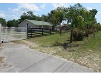 Ranch-style home with green roof, white fence and black post fence surrounding the perimeter of the property at 1737 Griffin Ave, Lady Lake, FL 32159