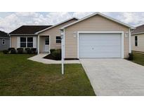 Charming home featuring an attached two-car garage, well-maintained lawn, and a welcoming front entrance at 2594 Berrington Loop, The Villages, FL 32162