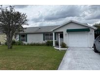 Charming single-story home featuring a two-car garage, well-maintained lawn, and classic vinyl siding at 528 Valencia Pl, Lady Lake, FL 32159