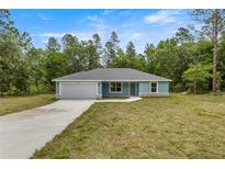 Charming single-story home featuring a well-manicured lawn, attached garage, and freshly painted exterior at 7299 Sw 202 Ct, Dunnellon, FL 34431