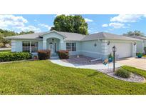 Charming single-story home featuring a well-manicured lawn and light blue exterior at 8722 Sw 60Th Cir, Ocala, FL 34476