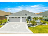 Charming single-story home featuring a well-manicured lawn, paver driveway, and a two-car garage under a bright blue sky at 907 Trifu Ter, The Villages, FL 32163