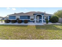 Charming blue single-story home with manicured landscaping, decorative rock, and an inviting entrance at 13115 Sw 49Th Ave, Ocala, FL 34473