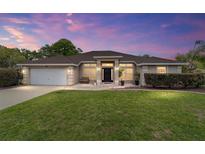 Charming single-story home with well-manicured lawn and inviting front entrance at dusk at 15 Sunrise Dr, Ocala, FL 34472